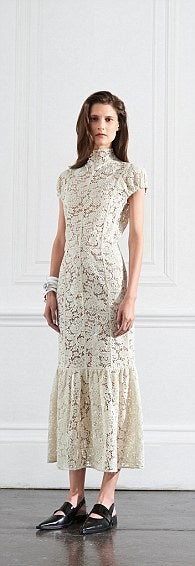 A woman modelling a Victoria Beckham Lace Midi Dress in Ivory. The background is white.