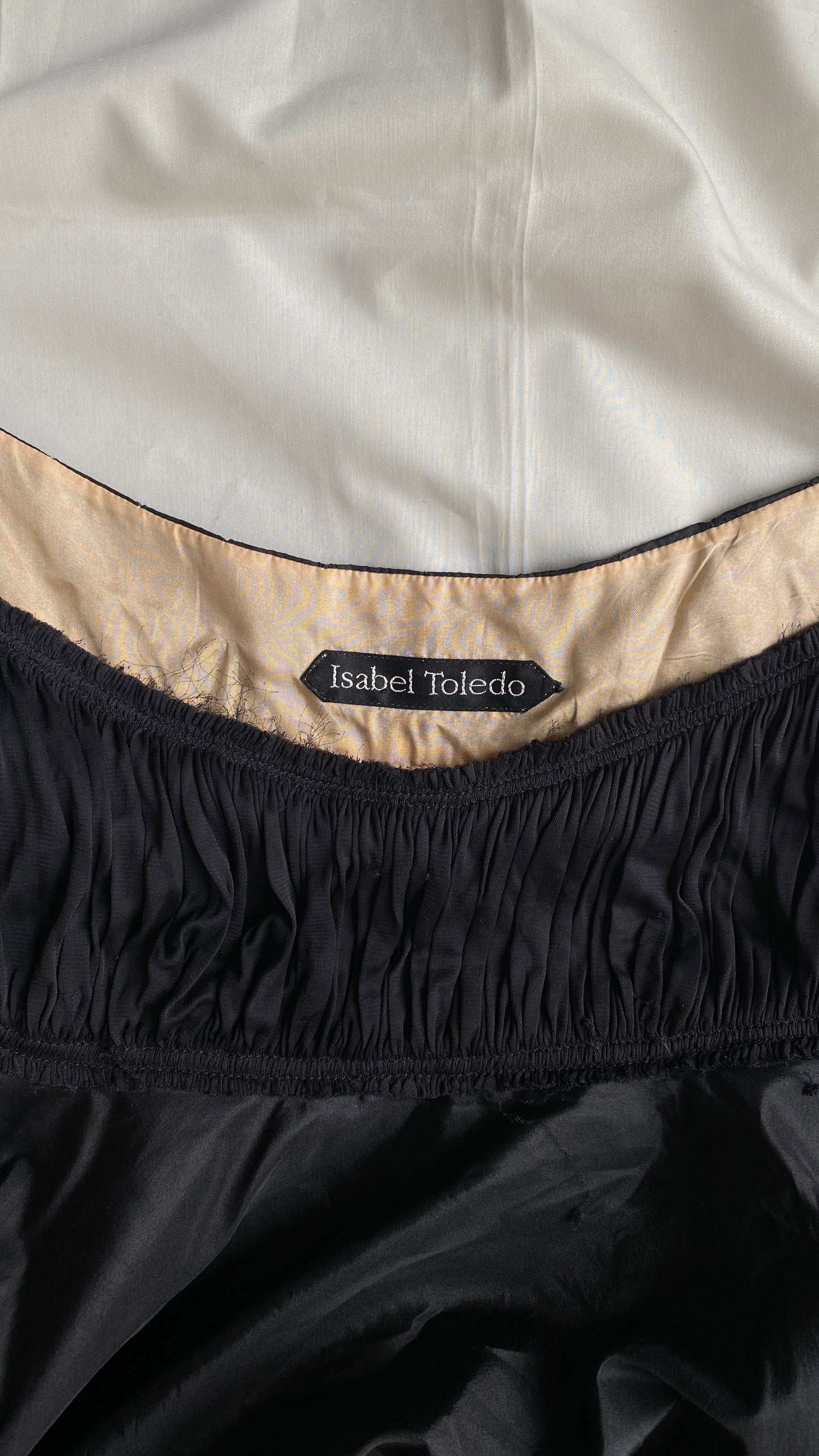 Close-up of the Isabel Toledo Sculptural Taffeta Dress neckline, showing the 'Isabel Toledo' label, beige interior lining, displayed on a white fabric background.