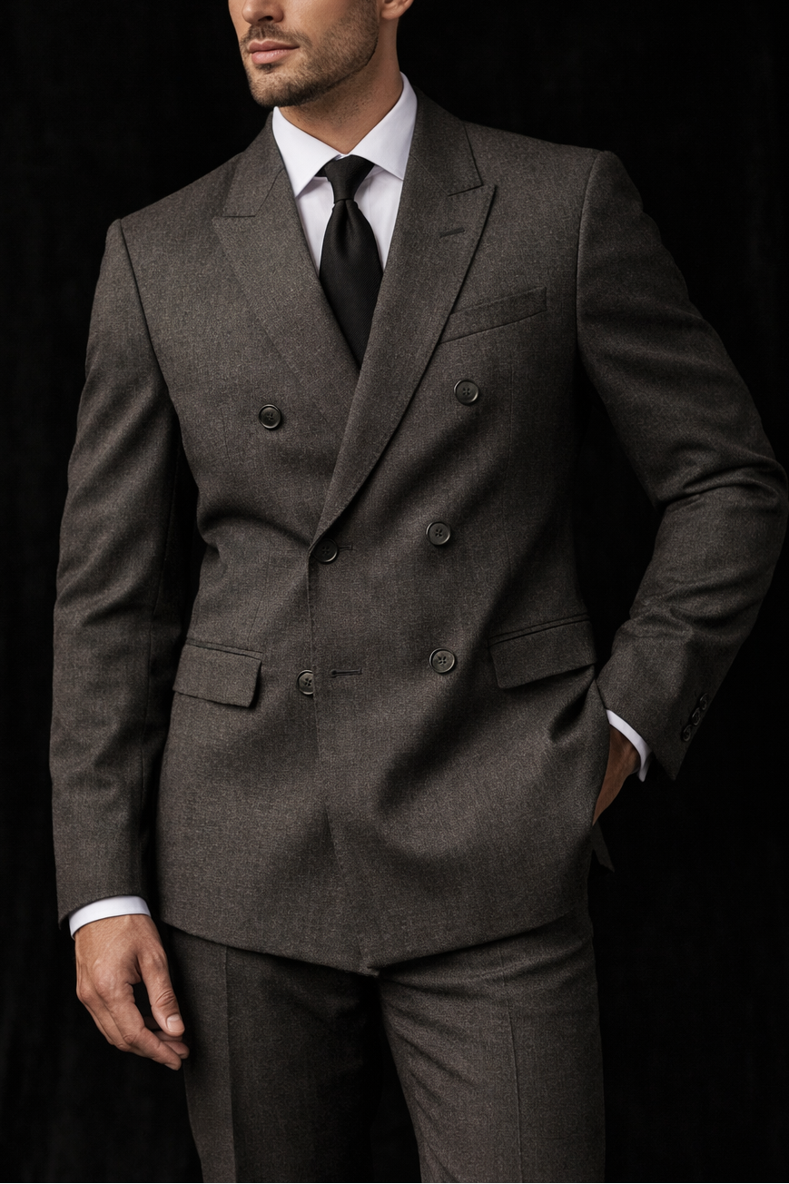A man modelling a gray Giorgio Armani Double-Breasted Jacket with a white shirt, a black tie, against a dark background. He wears gray trousers to match.