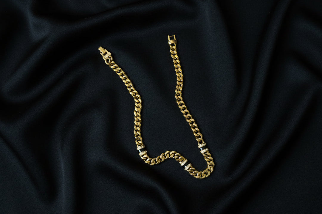 Swarovski Gold Curb Chain Necklace with Crystal & Black Enamel Accents on a black fabric background.