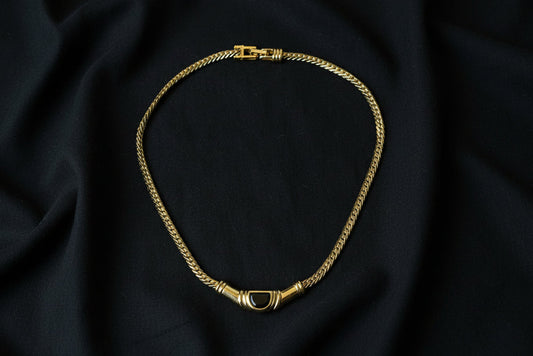 Swarovski Gold Necklace with Black Crystal Centre on the black fabric background.