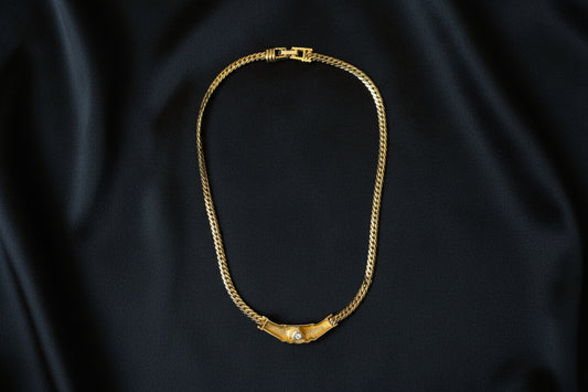 A view of the back of the Swarovski Gold Necklace with Black Crystal Centre on the black fabric. background.
