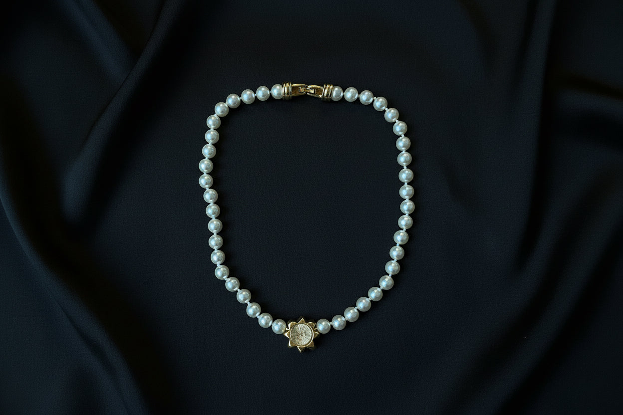 The back of a Swarovski Pearl Necklace with Geometric Crystal Centre. Set in gold-tone metal, sitting on a black fabric background.