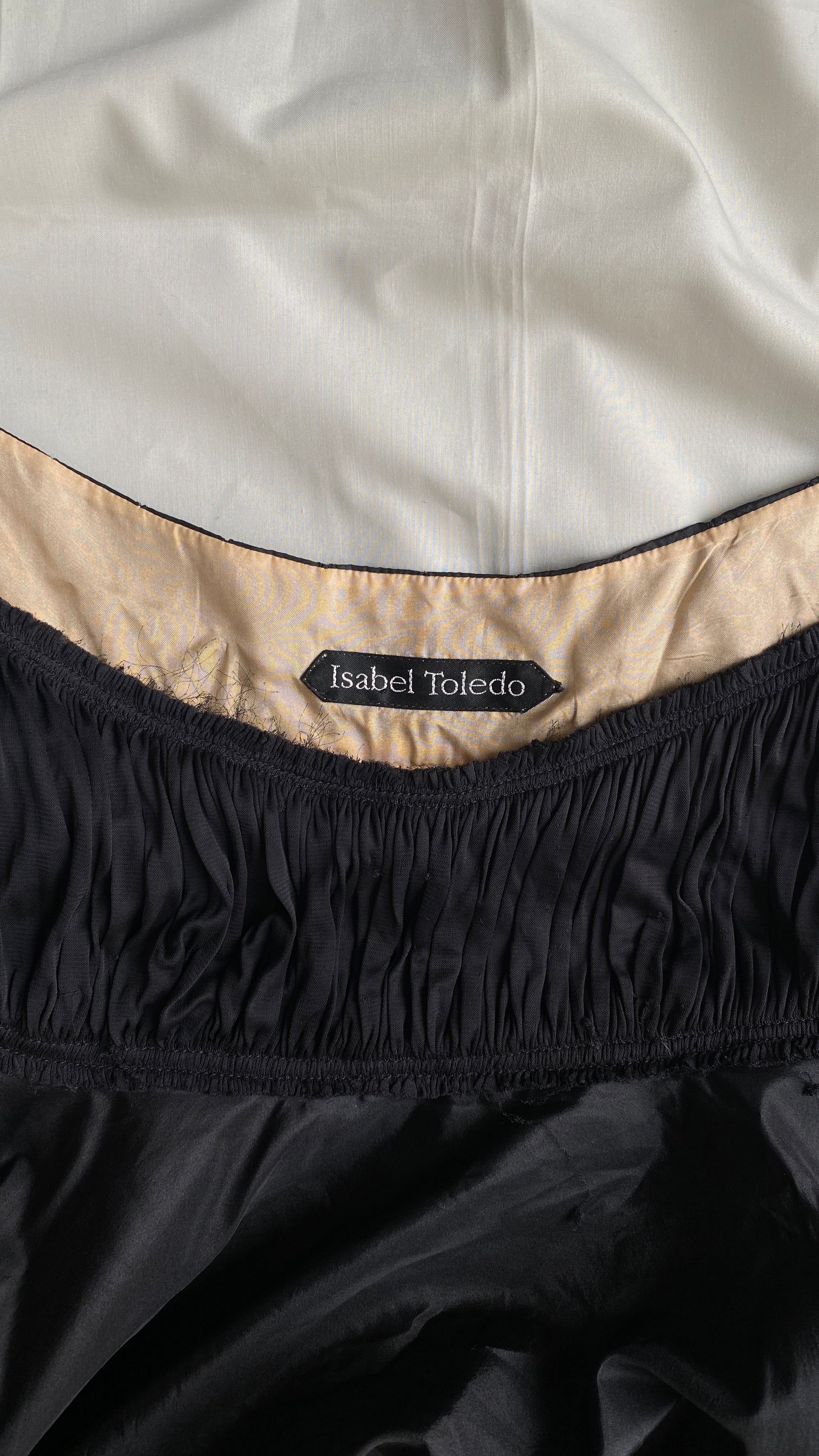 Close-up of the Isabel Toledo Sculptural Taffeta Dress neckline, showing the 'Isabel Toledo' label, beige interior lining, displayed on a white fabric background.