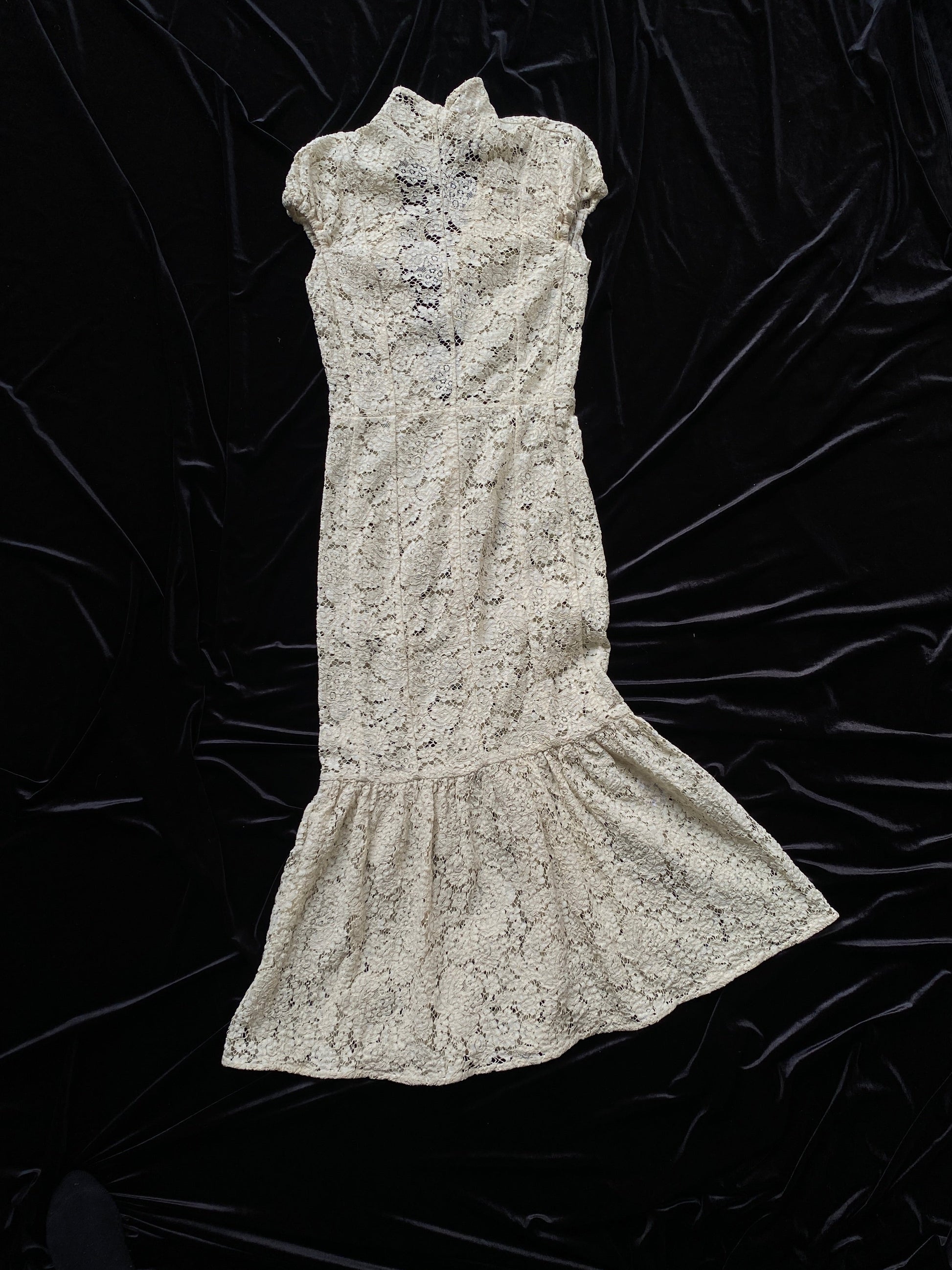 Victoria Beckham Lace Midi Dress in Ivory on a black fabric background.