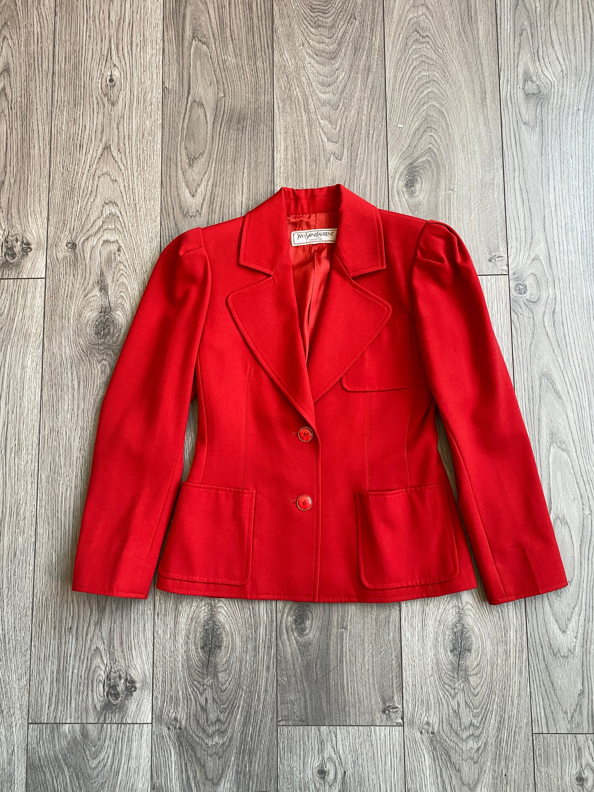 Vibrant red Yves Saint Laurent Rive Gauche Variation Jacket laid on a wooden floor.