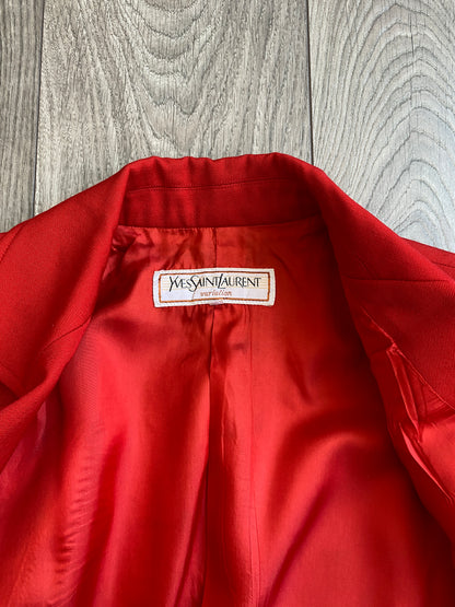 Close up view of the collar and lining, showing the label of the vibrant red Yves Saint Laurent Rive Gauche Variation Jacket, laid on a wooden floor.