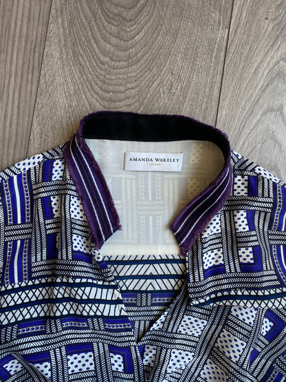 A close up image of the collar area of the Amanda Wakeley Silk Wrap Dress. Geometric print in shades of blue with the Amanda Wakeley label on display.